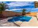 Refreshing backyard pool with rock feature and lush palm trees against a vibrant blue sky at 1588 S 226Th Dr, Buckeye, AZ 85326