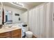 Bright bathroom featuring a vanity with wood cabinets, white toilet and shower/tub combination with white curtain at 1600 N Saba St # 177, Chandler, AZ 85225