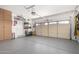 Clean and organized garage with epoxy flooring, storage cabinets, and an automatic door at 17574 W Gelding Dr, Surprise, AZ 85388