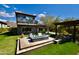 Beautiful backyard features a modern fire pit, green grass, and a second story balcony under a partly cloudy sky at 17594 N 98Th Way, Scottsdale, AZ 85255