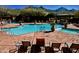 Community pool surrounded by lounge chairs, tables, and lush landscaping with mountain views at 17594 N 98Th Way, Scottsdale, AZ 85255