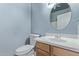 Light and airy powder bath with round mirror, wood vanity, and neutral color scheme at 18155 N Sterling Dr, Surprise, AZ 85374