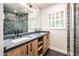 Elegant bathroom with dual sinks, a dark countertop, wood cabinets, and a glass-enclosed shower at 220 W San Juan Ave, Phoenix, AZ 85013