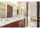 Bathroom featuring dual sinks, a large mirror, and a separate door to a connecting room at 3211 E Ian Dr, Phoenix, AZ 85042