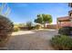 A spacious backyard featuring desert landscaping, a mature shade tree, and a concrete patio area at 3517 N Paseo Del Sol --, Mesa, AZ 85207