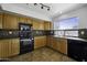 Traditional kitchen with wood cabinets, black appliances, and neutral backsplash at 4552 S 238Th Ln, Buckeye, AZ 85326