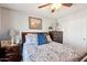 Cozy bedroom with a patterned queen bed, wood furniture, and a ceiling fan to provide a relaxing and comfortable space at 4979 E Colonial Dr, Chandler, AZ 85249