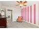 Bedroom featuring a chair, dresser, pink stripes, carpet floors, a window with blinds, a ceiling fan, and door at 4979 E Colonial Dr, Chandler, AZ 85249