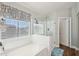 Bright bathroom featuring a bathtub with a glass shower enclosure and a large window at 4979 E Colonial Dr, Chandler, AZ 85249