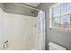 Bright bathroom featuring a shower with a decorative curtain, a window with blinds, grey walls, and white fixtures at 4979 E Colonial Dr, Chandler, AZ 85249