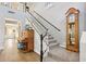 Elegant staircase with carpeted steps, white railings, black accents, and a decorative grandfather clock at 4979 E Colonial Dr, Chandler, AZ 85249