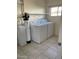 A laundry room featuring a washer, dryer, water filtration system, shelving, and tiled floors at 6607 W Osborn Rd, Phoenix, AZ 85033