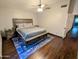 Spacious bedroom with a ceiling fan, hardwood floors, and a large bed on a blue rug at 6901 W Marco Polo Rd, Glendale, AZ 85308