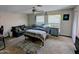 Spacious bedroom featuring a ceiling fan, two windows, carpeted floors, and gray accent sofa at 6901 W Marco Polo Rd, Glendale, AZ 85308