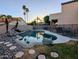 A backyard showcases an in-ground pool, rock features, and cozy seating surrounded by lush landscaping at 6901 W Marco Polo Rd, Glendale, AZ 85308