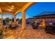 Expansive backyard with an outdoor kitchen, patio seating, fire pit, and lush desert landscaping at 706 E La Palta St, Queen Creek, AZ 85140