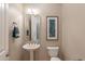 Bathroom featuring a pedestal sink, toilet, stylish mirror, decorative wall art, and neutral color palette at 706 E La Palta St, Queen Creek, AZ 85140