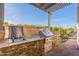 Outdoor kitchen boasts stainless steel appliances, a sink, and a grill nestled in a stone counter under a modern pergola at 706 E La Palta St, Queen Creek, AZ 85140