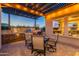Inviting outdoor kitchen with stainless steel grill, stone counter, and cozy seating under a pergola with string lights at 706 E La Palta St, Queen Creek, AZ 85140