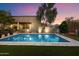 Beautiful backyard pool with lush greenery, outdoor lighting, and a covered patio at 8845 E Sierra Pinta Dr, Scottsdale, AZ 85255