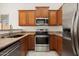 Modern kitchen with stainless steel appliances, granite countertops, wood cabinets and sink with views out the window at 8962 W Grovers Ave, Peoria, AZ 85382