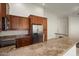 Kitchen with granite countertops, stainless-steel refrigerator, and wooden cabinetry, creating a blend of style and functionality at 8962 W Grovers Ave, Peoria, AZ 85382