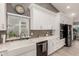 Kitchen featuring a farmhouse sink, white cabinets, quartz countertops and a tiled backsplash at 950 W Cooley Dr, Gilbert, AZ 85233