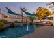 Inviting pool area with a fire feature, rock waterfall, and shade sails at 950 W Cooley Dr, Gilbert, AZ 85233