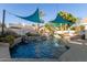 Backyard pool with sun shades, waterfall features, and lush landscaping at 950 W Cooley Dr, Gilbert, AZ 85233