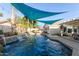 Beautiful pool with lush landscaping, rock waterfall feature, shade sails, and an outdoor seating area at 950 W Cooley Dr, Gilbert, AZ 85233