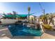 Backyard pool featuring a rock waterfall, turquoise shade sails, tropical plants, and string lights at 950 W Cooley Dr, Gilbert, AZ 85233