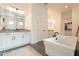 Bathroom featuring double sinks, a modern tub, a glass-enclosed shower, and white cabinetry at 9960 E Strobe Ave, Mesa, AZ 85212