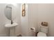 Elegant powder room with pedestal sink, round mirror and decorative wall art creates a welcoming ambiance at 9960 E Strobe Ave, Mesa, AZ 85212