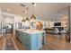 Open kitchen boasts an island with seating, modern lighting, and seamless access to the living area at 9960 E Strobe Ave, Mesa, AZ 85212