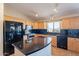 Well-lit kitchen with black appliances, a black countertop island, and light wood cabinetry at 10368 E Gold Nugget Ct, Gold Canyon, AZ 85118