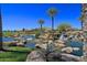 Lush community water feature with rocks, waterfall, palm trees, and blue sky background at 1474 E Elysian Pass, Queen Creek, AZ 85140