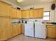 Laundry room with wooden cabinets, a sink, a window, and a washer and dryer set at 15720 S Lanai Cir, Arizona City, AZ 85123