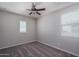 An empty bedroom with neutral walls, carpet, and a ceiling fan and two windows at 16227 W Mariposa Grande --, Surprise, AZ 85387
