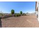 Expansive backyard featuring mature trees, a rock ground cover, and block wall at 18369 W La Senda Dr, Surprise, AZ 85387