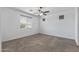 A light-filled bedroom with plush carpeting, a ceiling fan, and large window at 18369 W La Senda Dr, Surprise, AZ 85387
