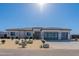 A modern home showcases a desert landscape, complemented by a three-car garage with black framed glass doors at 20256 W Highland Ave, Litchfield Park, AZ 85340