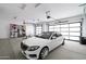 A clean, organized garage showcasing a white luxury car, storage racks, bicycle and a well-lit interior at 20256 W Highland Ave, Litchfield Park, AZ 85340