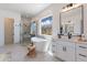 Luxurious bathroom featuring a soaking tub, a large window with a view, and elegant white cabinetry at 20277 W Highland Ave, Litchfield Park, AZ 85340