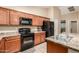 Functional kitchen features wooden cabinets, black appliances, and a tiled floor at 2110 S 102Nd Ln, Tolleson, AZ 85353