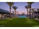 Community pool surrounded by palm trees, cabanas, and lawn chairs at dusk at 2232 W Chisum Trl, Phoenix, AZ 85085