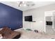 Bedroom featuring a blue accent wall, large TV, ceiling fan, and carpet, plus an open doorway at 2602 E Glass Ln, Phoenix, AZ 85042