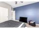 Bedroom featuring blue accent wall and a black TV, neutral carpet, plus a white door at 2602 E Glass Ln, Phoenix, AZ 85042