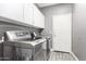 Well-lit laundry room with gray walls, white cabinets and modern washer and dryer at 2602 E Glass Ln, Phoenix, AZ 85042