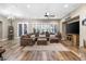 Spacious living room featuring wood floors, plantation shutters, a ceiling fan, and a large brown sectional couch at 27016 N 20Th Ln, Phoenix, AZ 85085