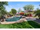 Backyard pool with mature landscaping, a built-in spa, rock waterfalls, poolside seating, and a lush green lawn at 27016 N 20Th Ln, Phoenix, AZ 85085